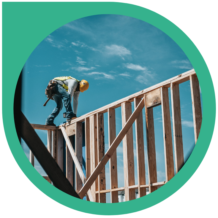 Circular graphic with a construction worker on a wood house frame.